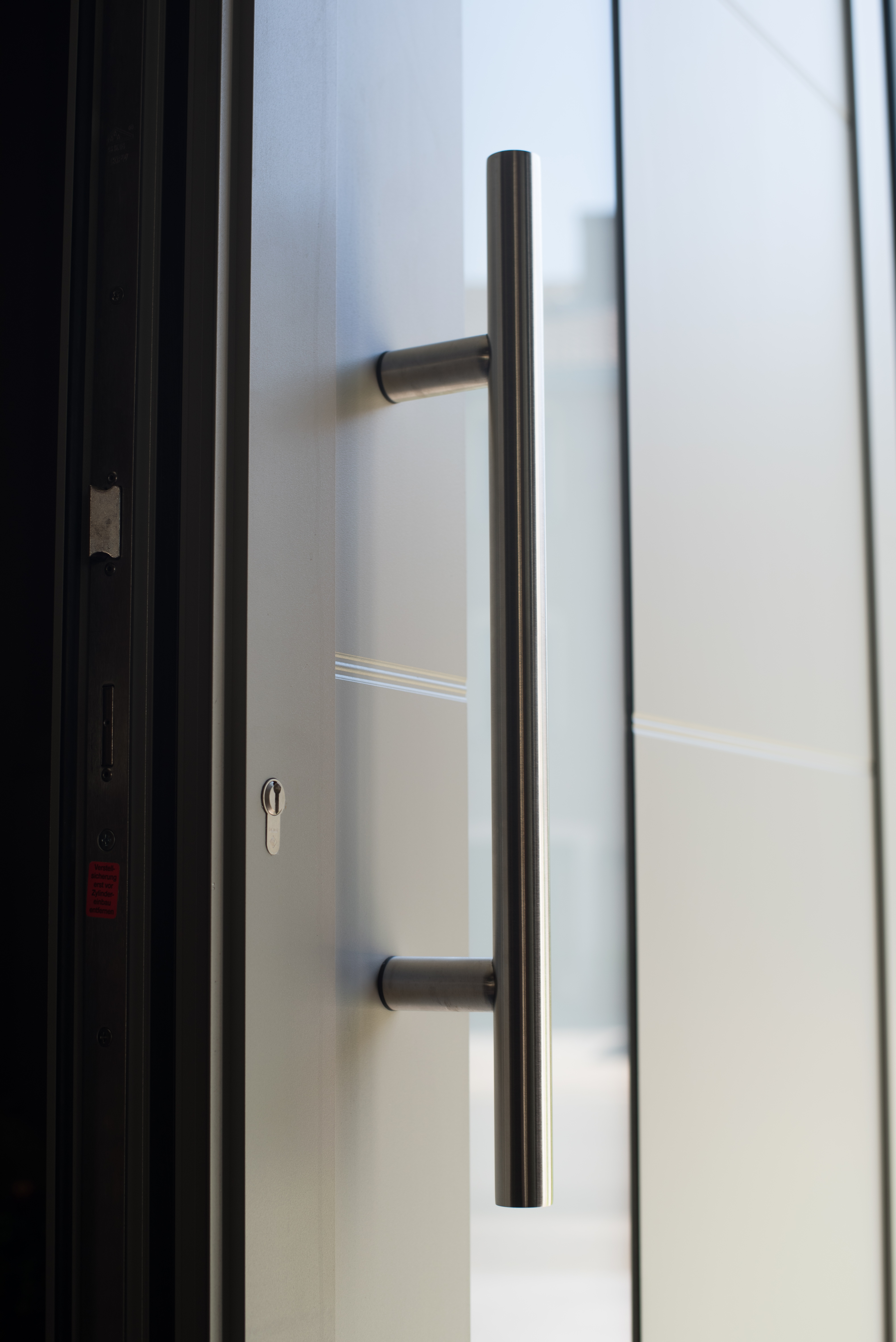 Halfbeglaasde deur met lange verticale handgreep in de gerenoveerde gevel van een driegevelwoning.