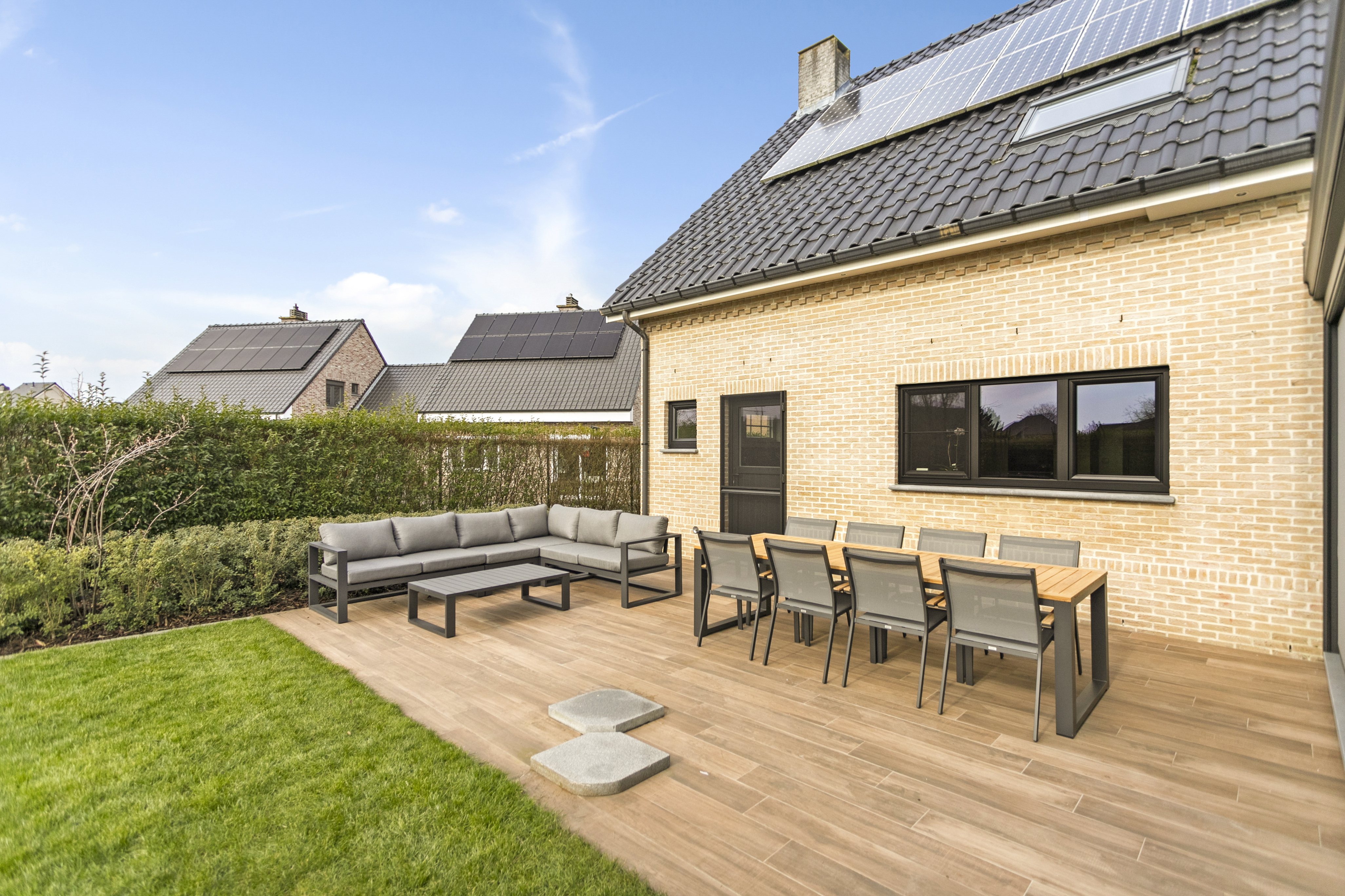 Gerenoveerde landelijke woning met matzwarte PVC-ramen, een driedubbel draai-kipraam en een semi-beglaasde deur aan een ruim terras.