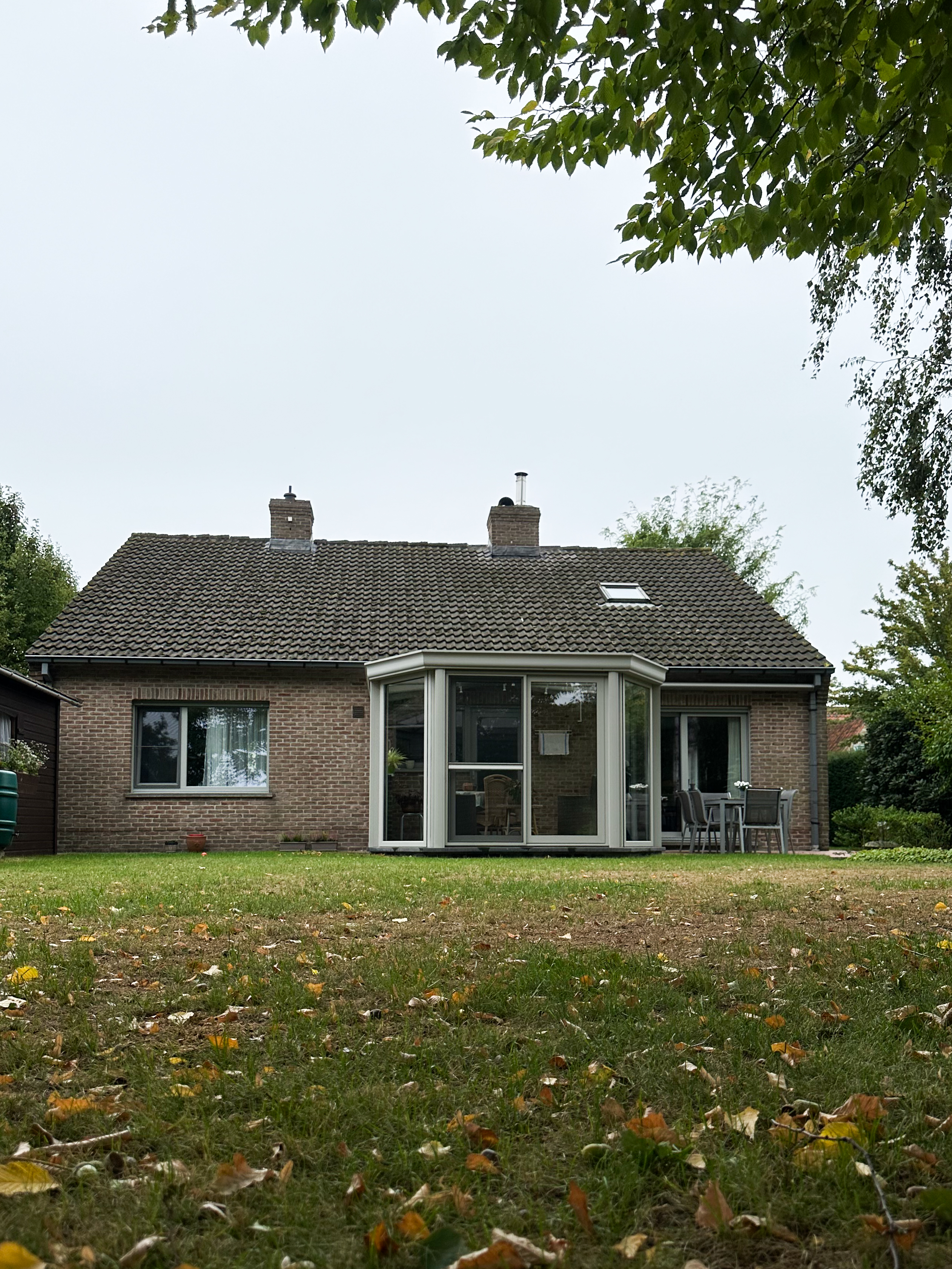 Woning met grijze raamprofielen in Agaatgrijs NERF: een brede combinatie van een vast raam en een draai-kipraam geeft uit op het overdekte terras.