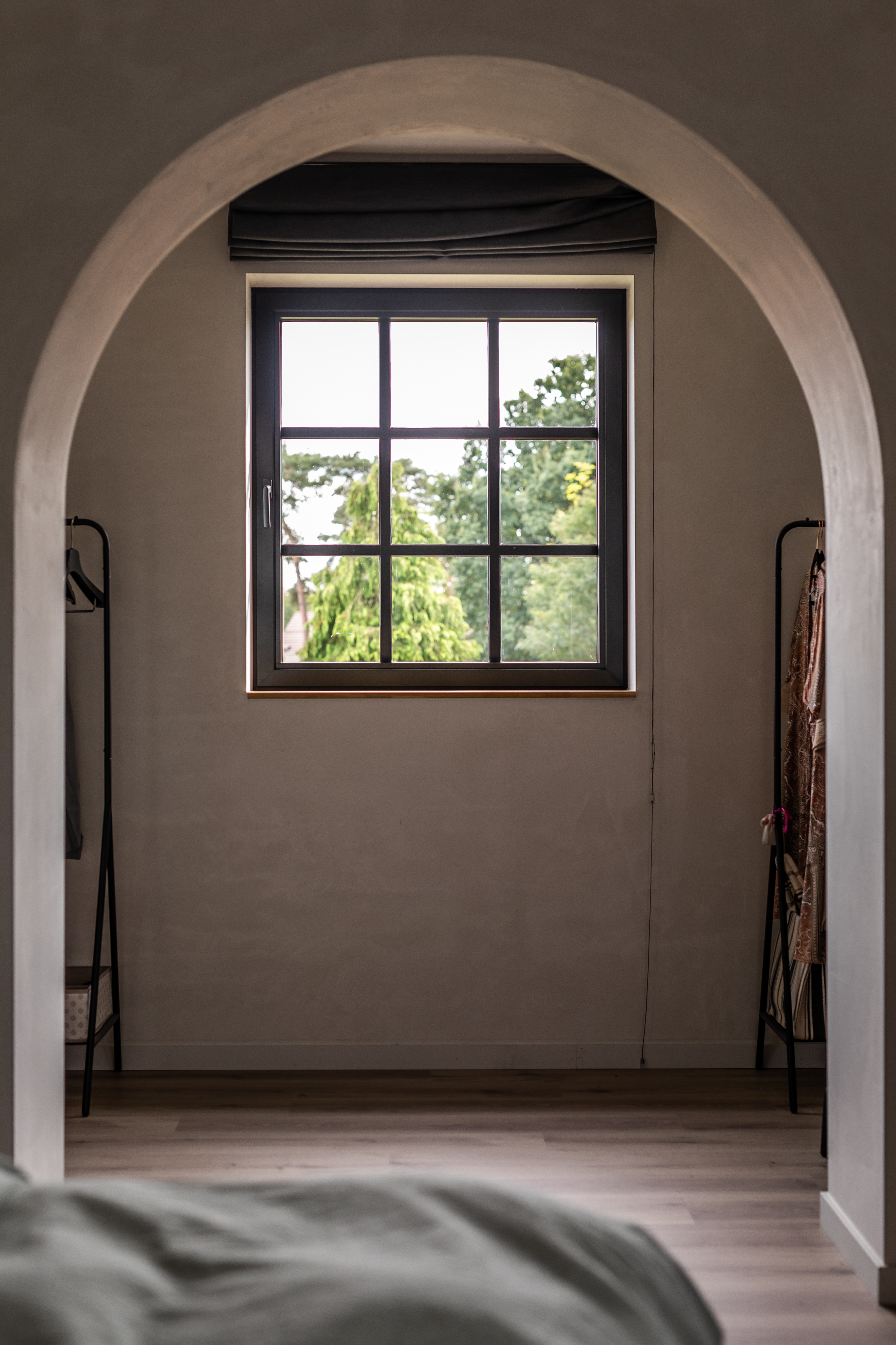 Zwart draai-kipraam in een warm, landelijk interieur, geplaatst in een ronde doorgang met zicht op het groen buiten.
