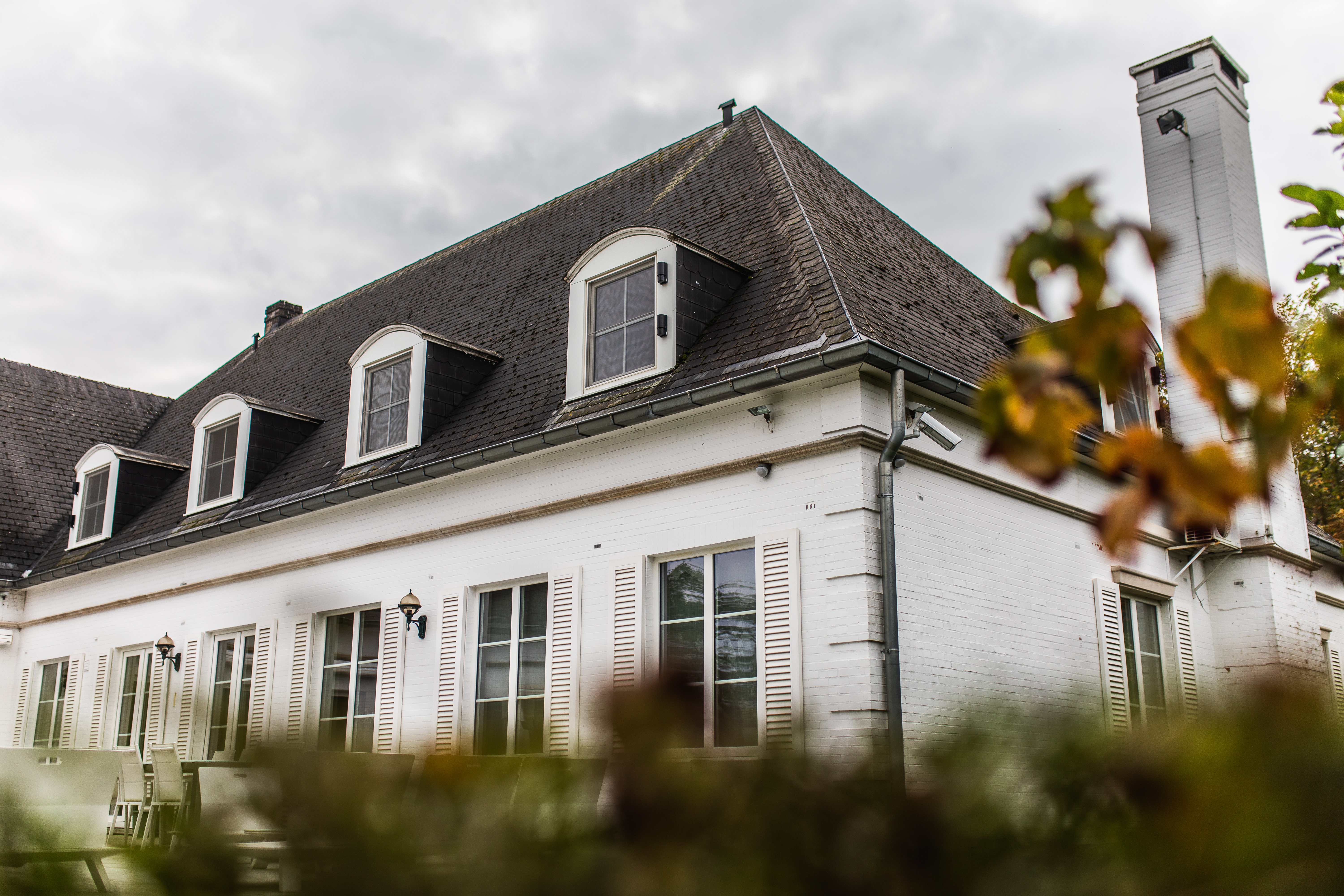 Gerenoveerde vrijstaande woning in verfijnd klassieke stijl, met witte gevel, donker dak, dakramen en hoge ramen met luiken.