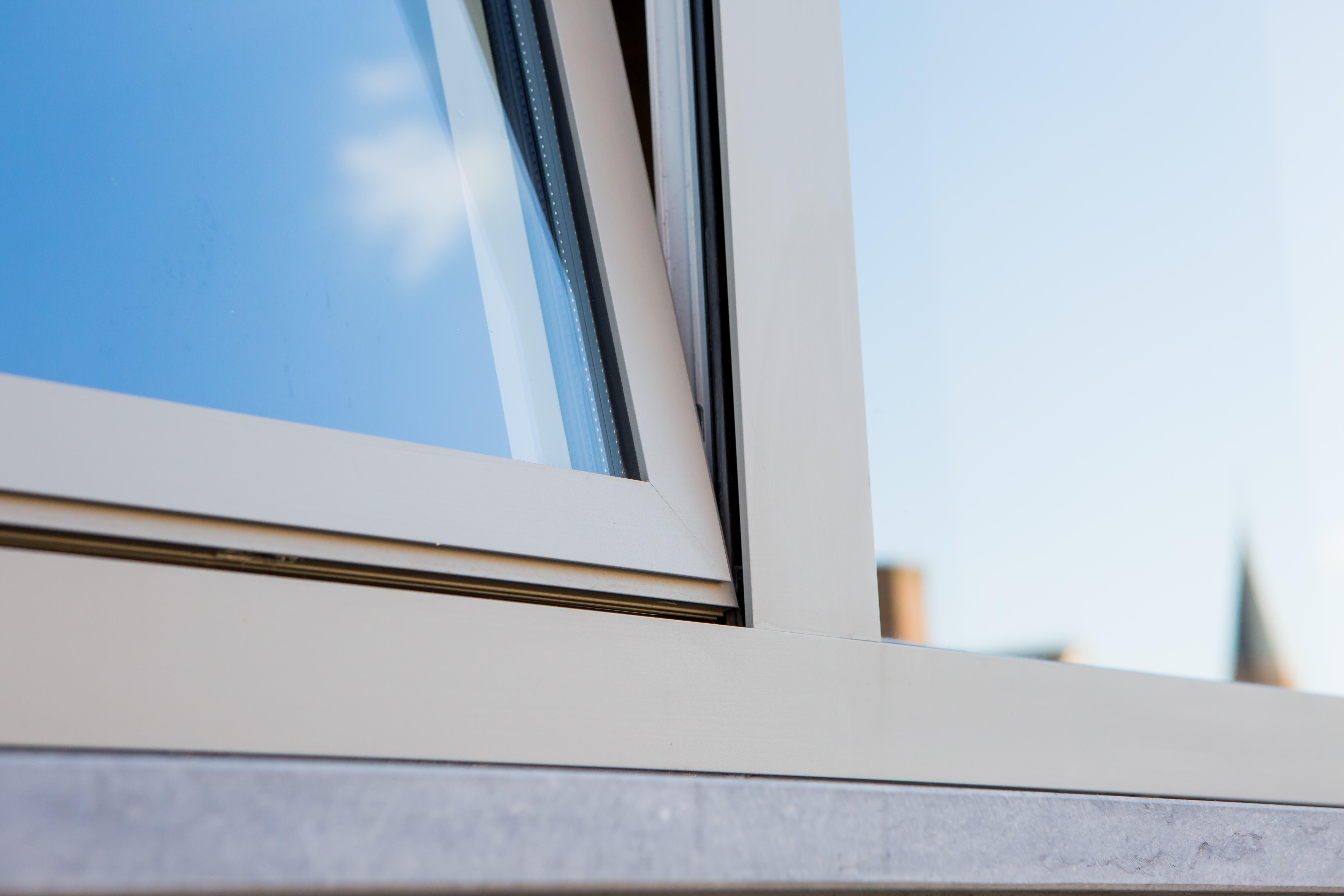 Detail van een witte, semi-beglaasde deur met smal raamprofiel en glasvlak tijdens een renovatie.