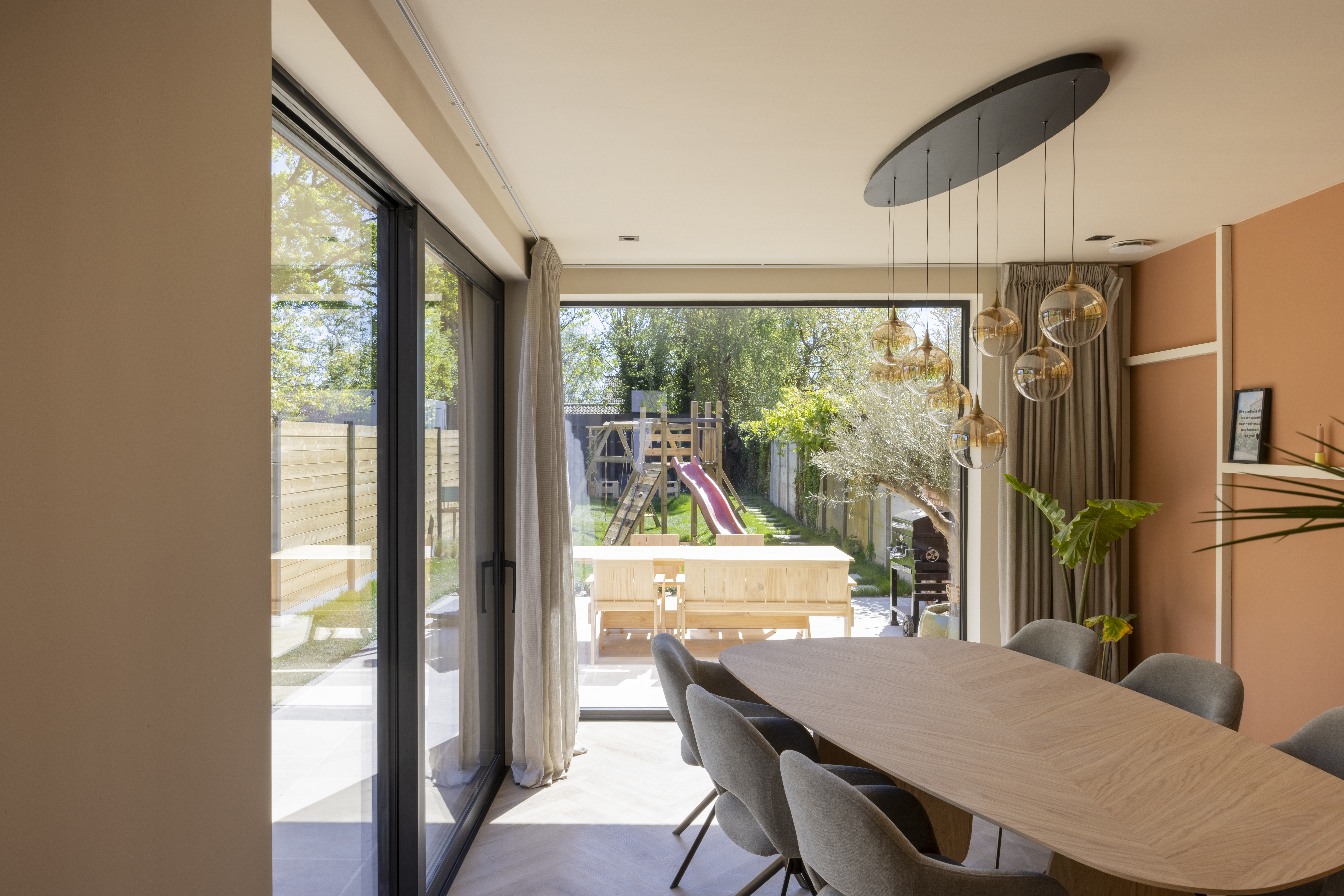 Vast raam uit de serie Komfort EVO small met signaalzwarte aluminiumprofielen en ALU Visoglide Monorail in een lichte eetruimte met zicht op de tuin.