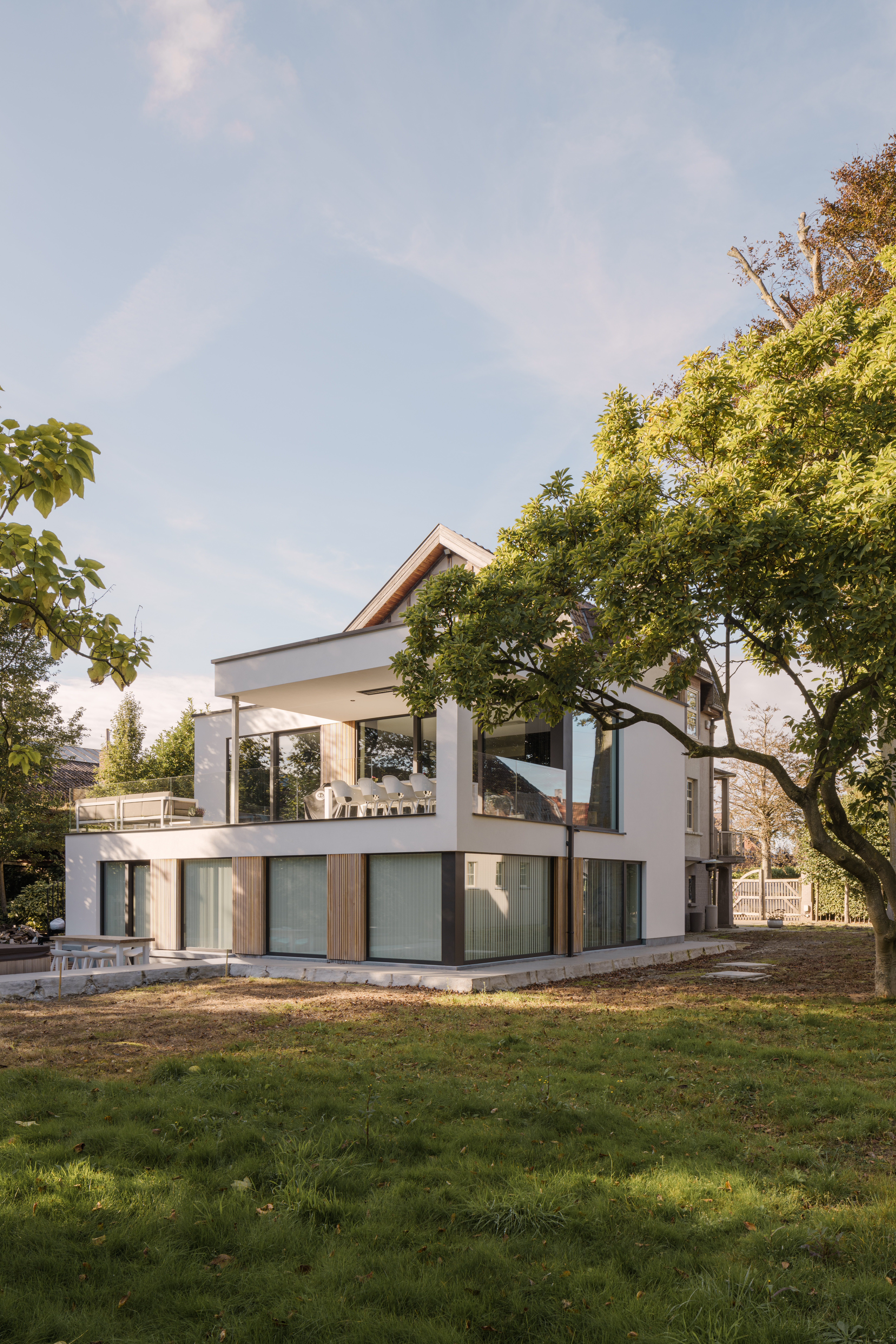 Moderne vrijstaande nieuwbouwwoning met grote vaste ramen in zwarte raamprofielen, een strakke architectuur en karaktervolle uitstraling, omgeven door een groene tuin.