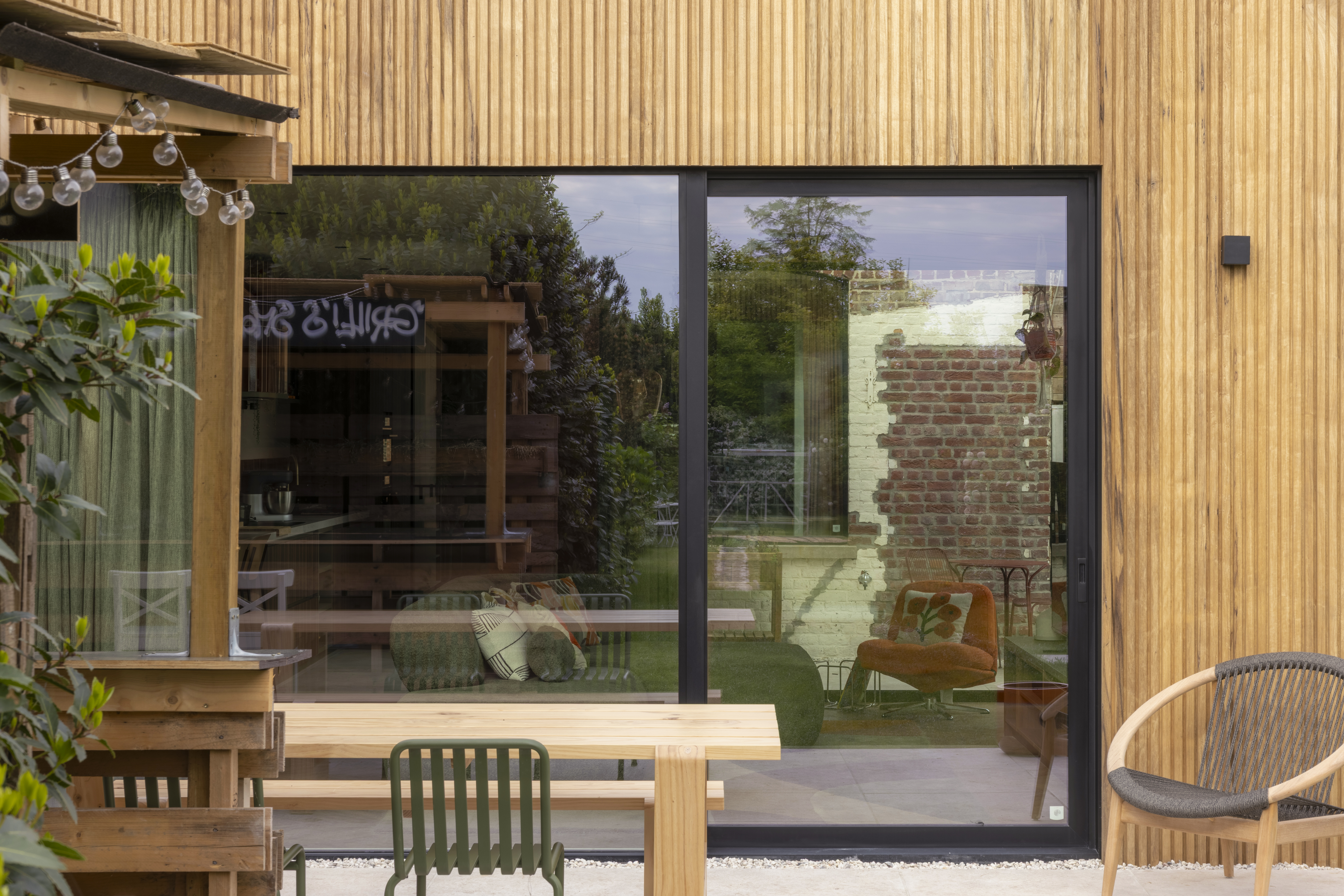 Zwart aluminium schuifraam met ALU Visoglide Monorail-profielen in diepzwart, geïntegreerd in een houten gevel met zicht op het terras en interieur.