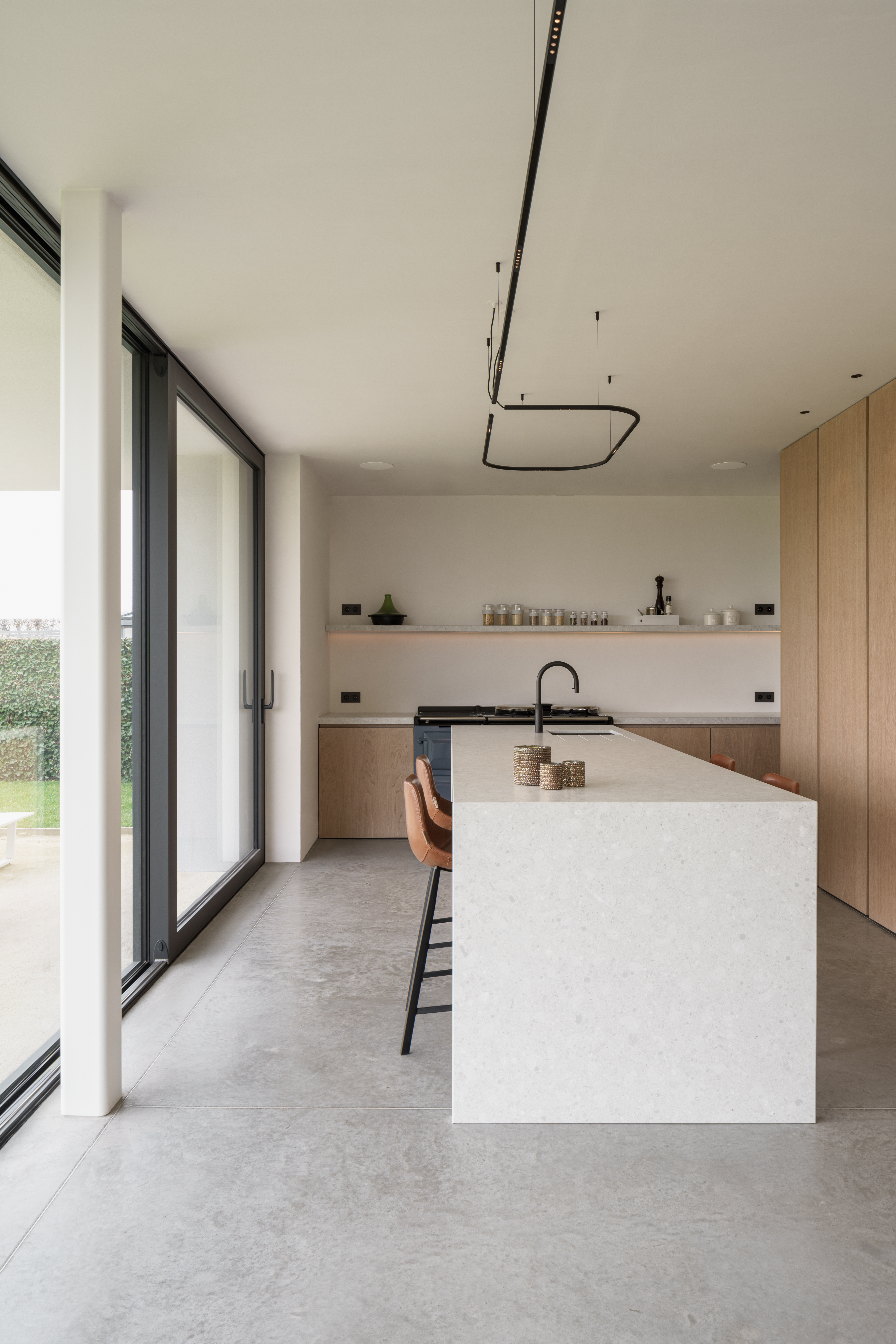 Modern keukeninterieur in een nieuwbouwwoning met grote zwarte ALU Ultraglide Monorail-schuiframen en strakke, eigentijdse lijnen.