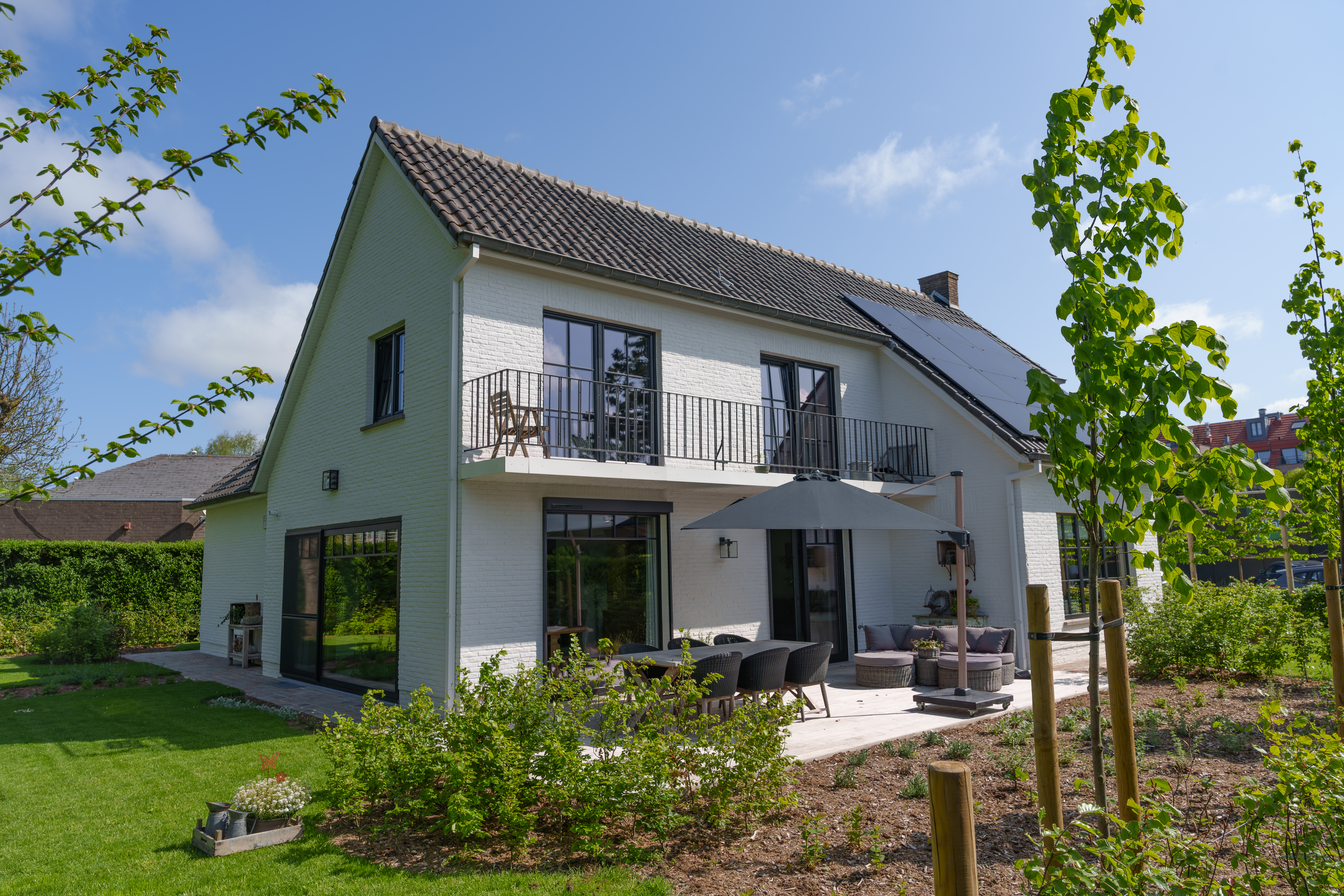 Gerenoveerde vrijstaande woning met matzwarte dubbele, draai-kip- en vaste ramen, deels met voorzetrolluiken, in een warme landelijke stijl en met terras.