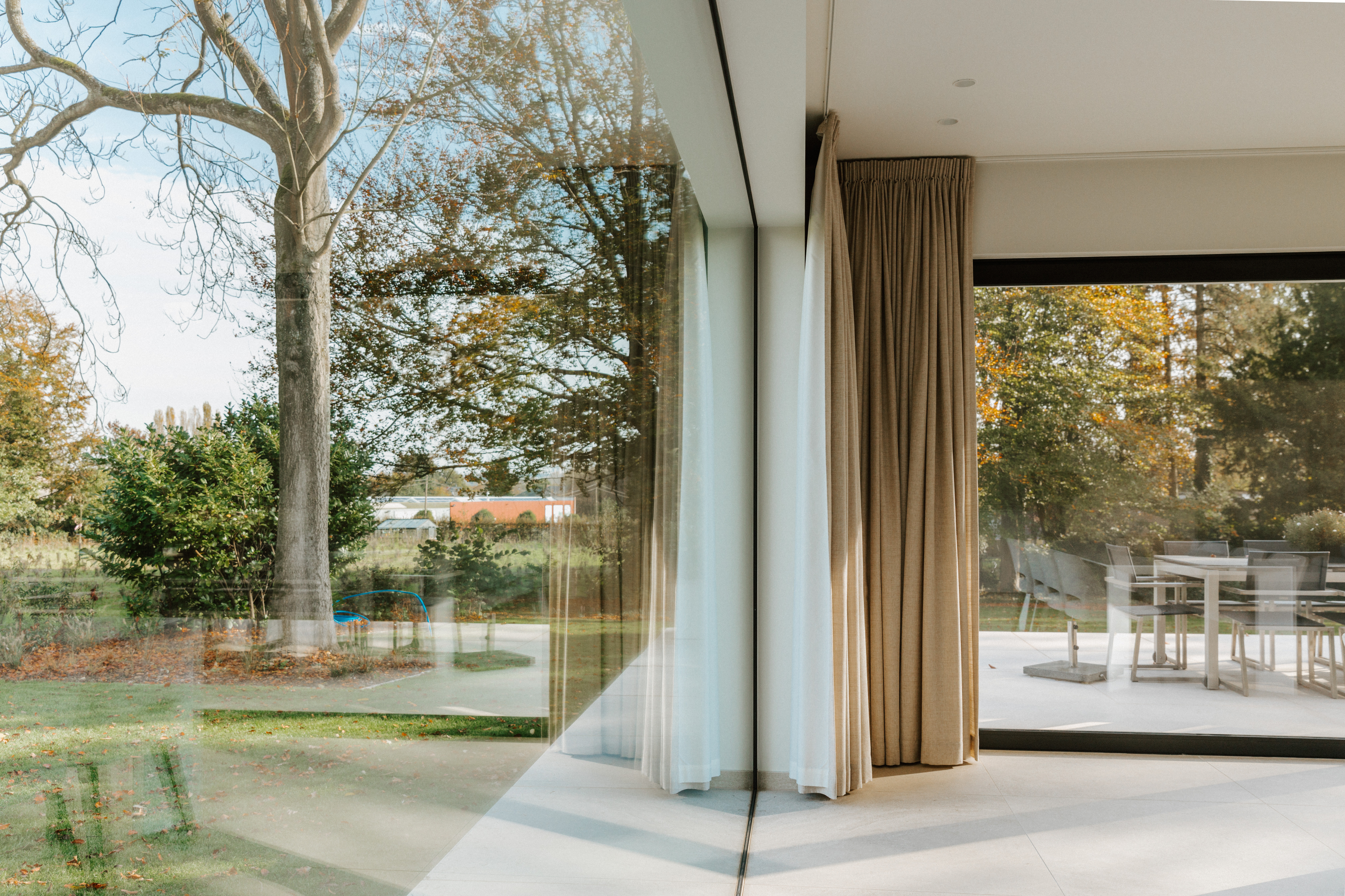 Intérieur moderne rénové avec baie coulissante noire ALU Visoglide Monorail du système Koncept PLUS, ouverte sur le jardin et la terrasse.