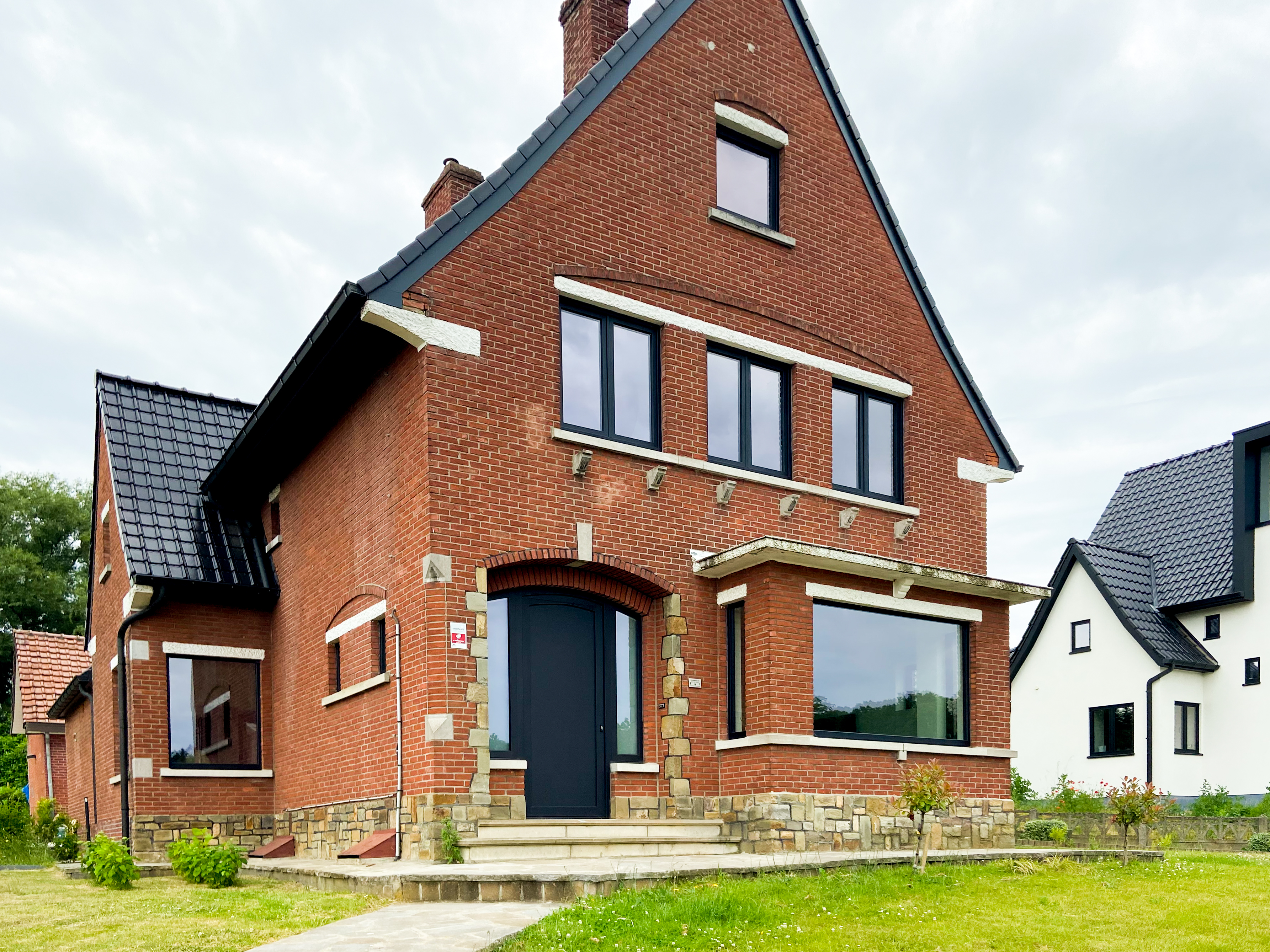 Gerenoveerde vrijstaande bakstenen woning met matzwarte ramen, een voordeur met dubbel zijlicht en een groot raam in de voorgevel.