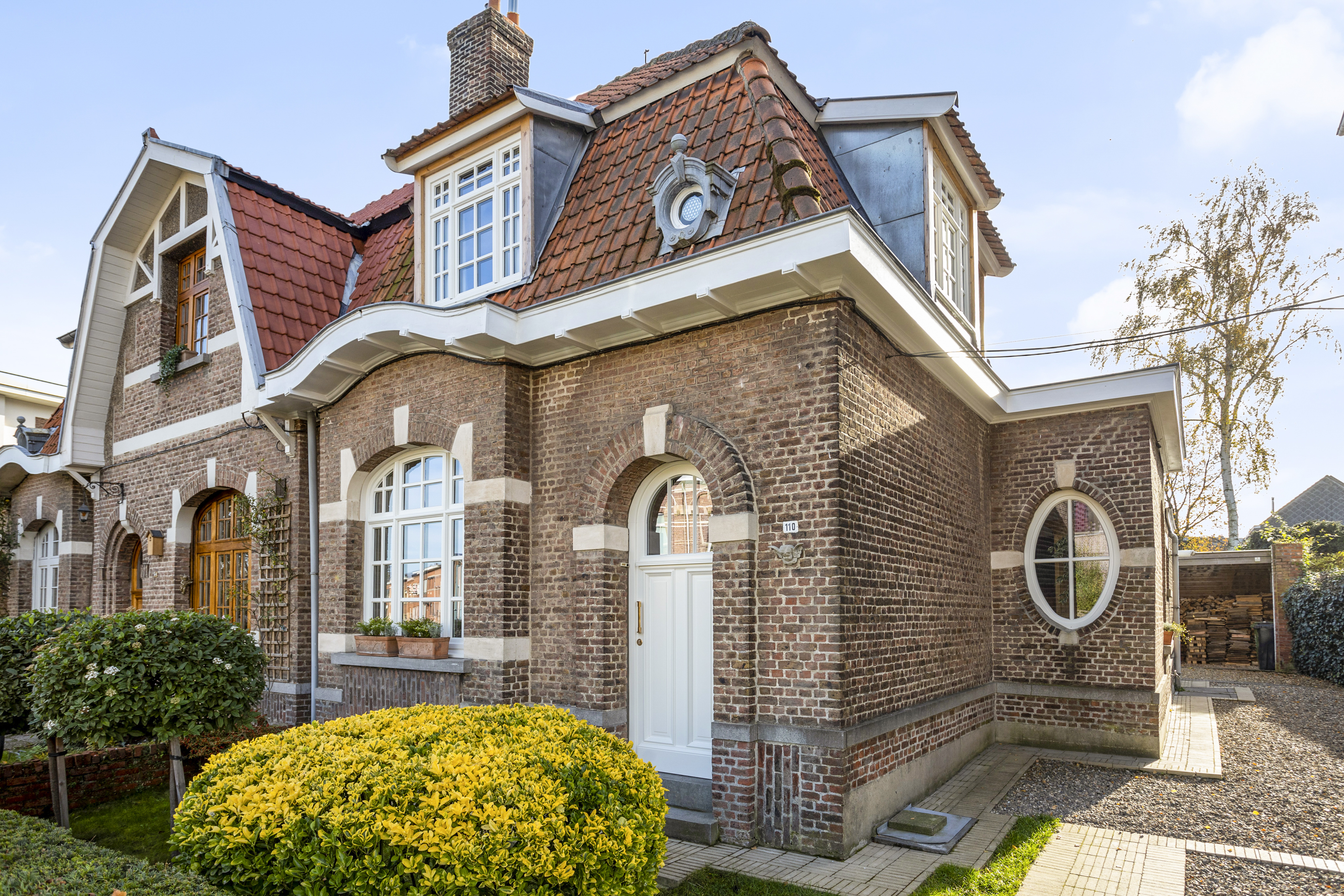 Witte, afgelakte ramen en een raam met bovenlicht in de bakstenen gevel van een karaktervolle woning.