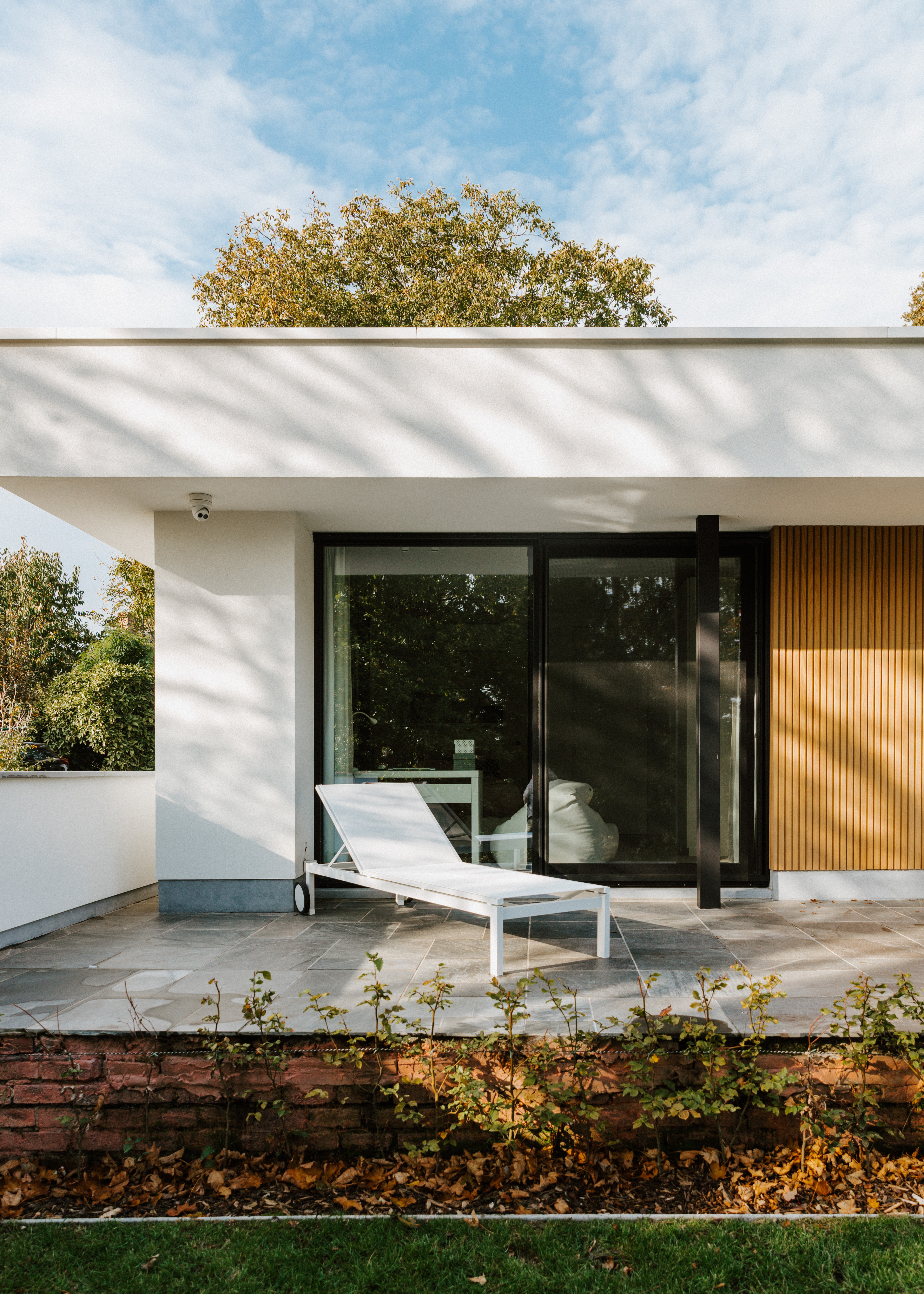 Modern gerenoveerde vrijstaande woning met een zwart aluminium ALU Visoglide Monorail-schuifraam en schuifvliegenraam aan een overdekt terras.