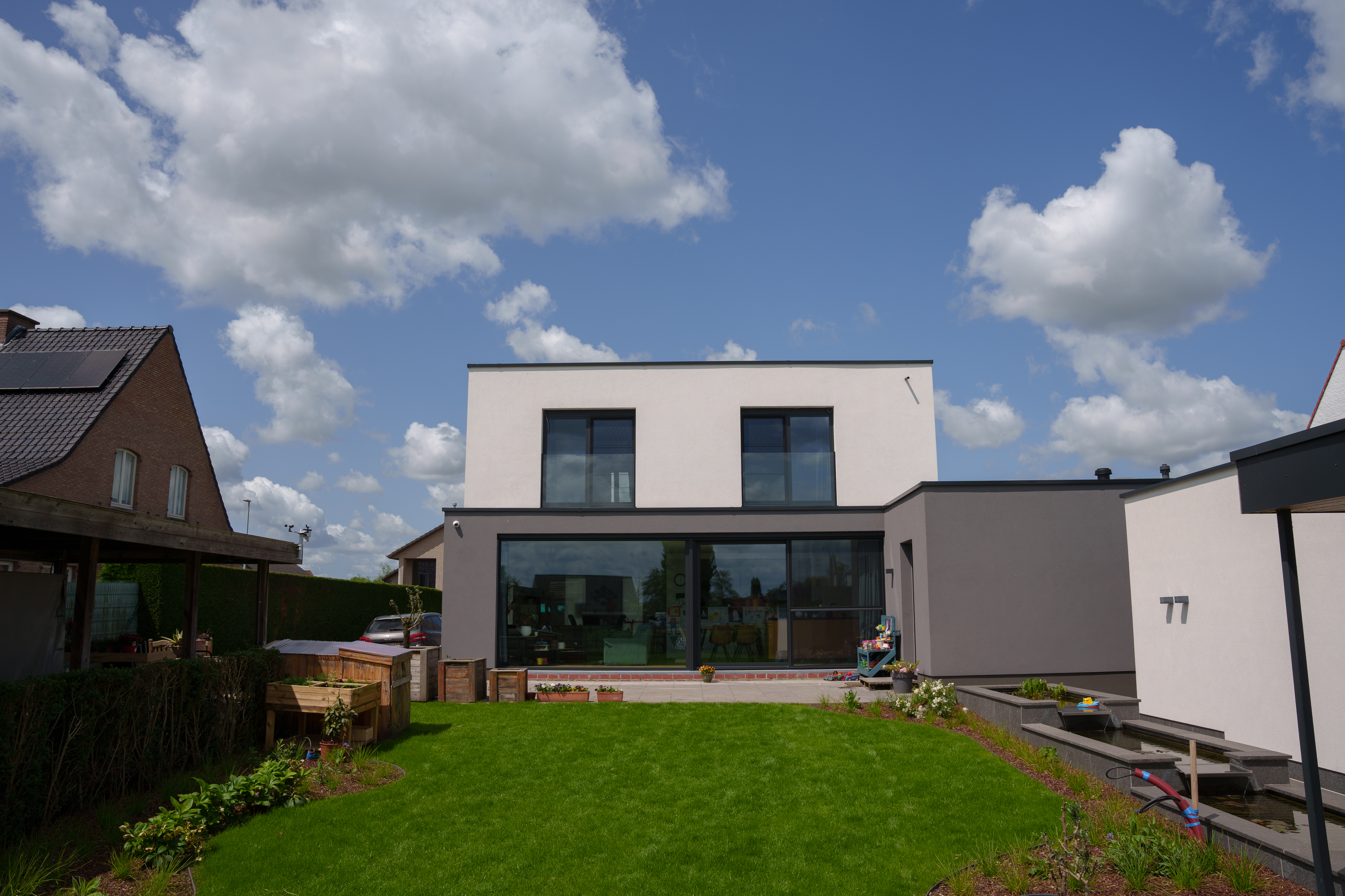 Moderne vrijstaande woning met diepzwarte aluminium ramen, vaste ramen, een draai-kipraam en brede schuiframen aan de tuinzijde.