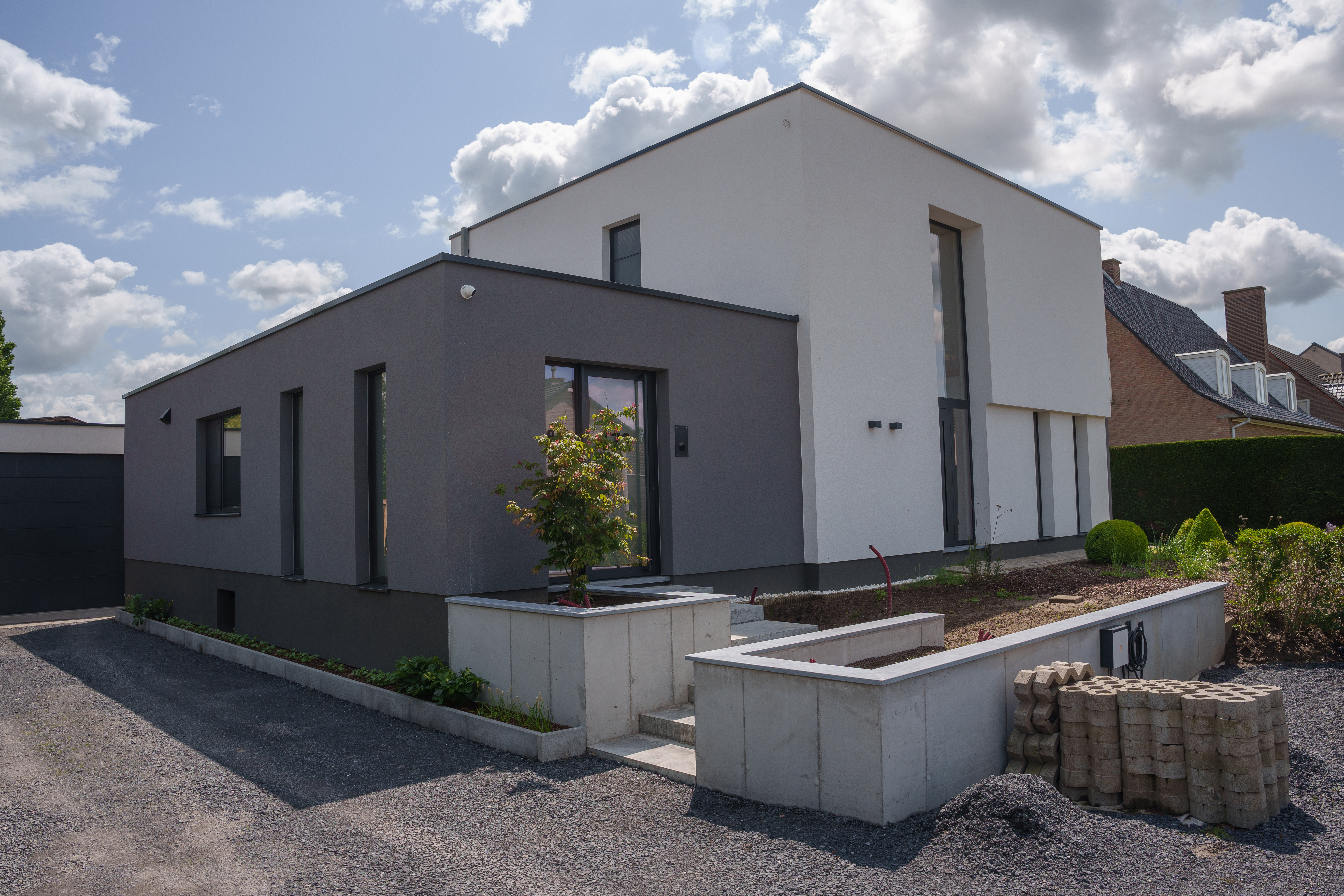 Moderne vrijstaande nieuwbouwwoning met zwarte aluminium ramen, een beglaasde deur met zijlicht en strakke gevels.