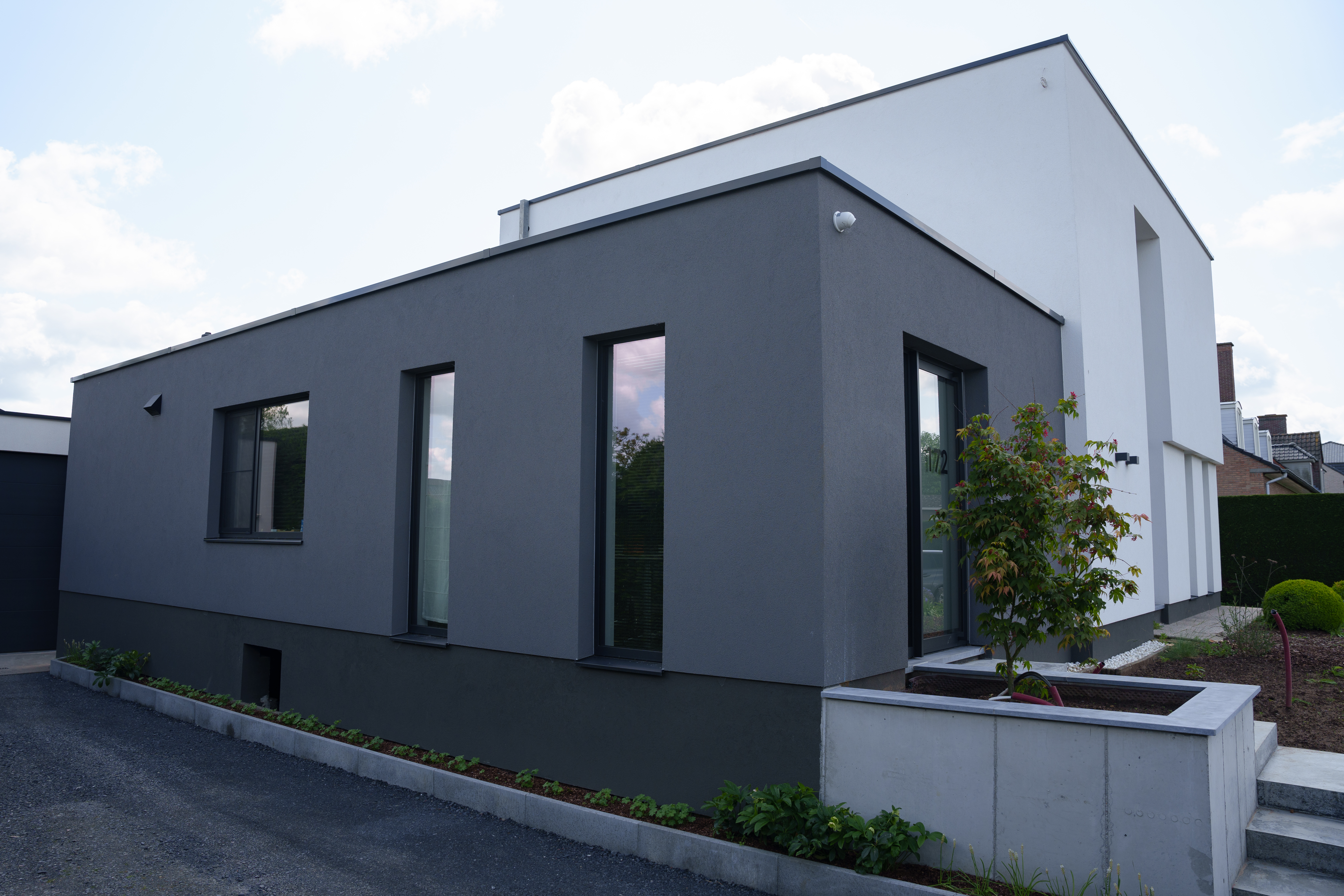 Moderne vrijstaande nieuwbouwwoning met diepzwarte aluminiumprofielen, vaste ramen, dubbele ramen, draai-kipramen en een beglaasde deur in de donkere gevel.