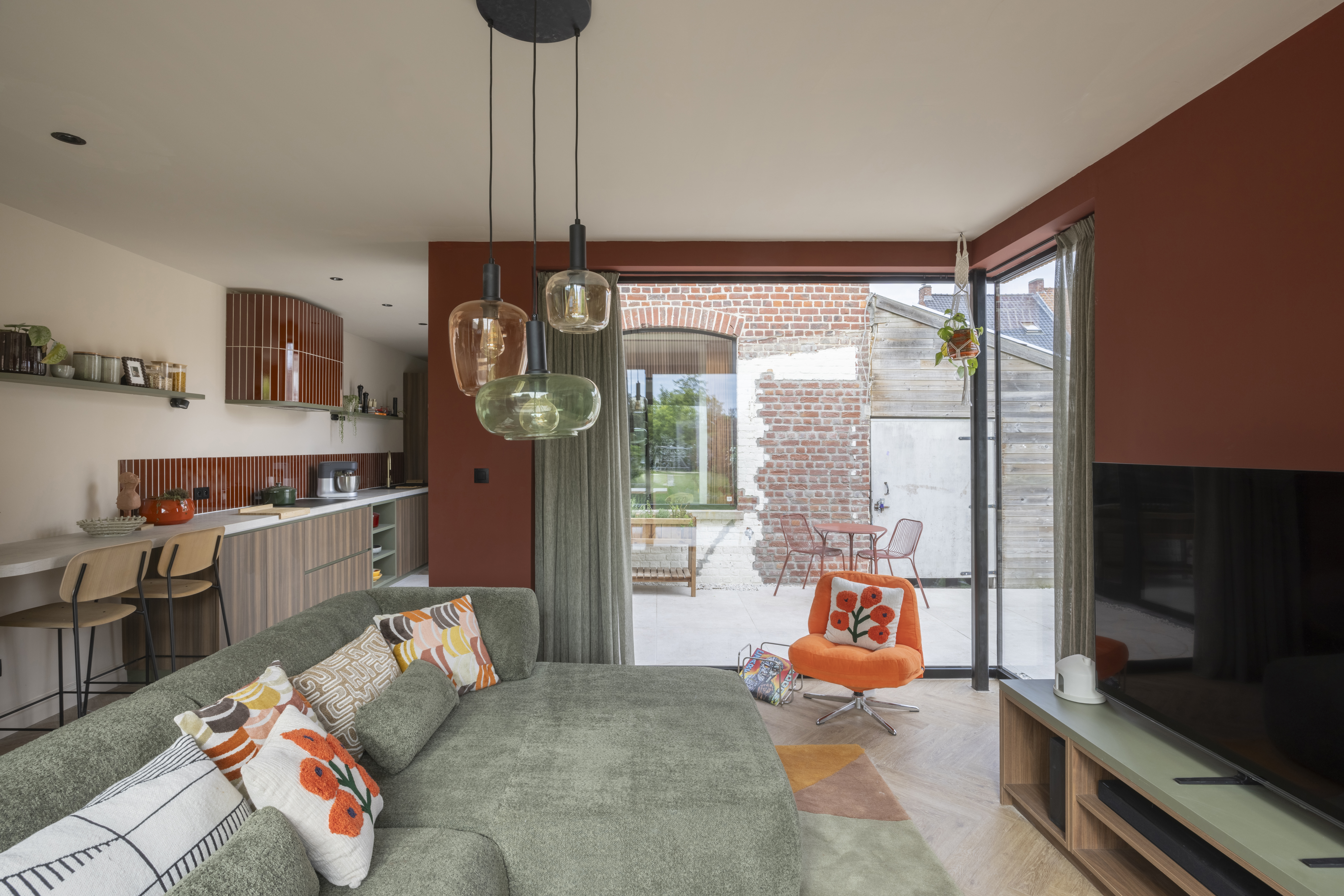 Modern interieur met een vast raam uit de Komfort EVO small-reeks en diepzwarte raamprofielen, naast een open terras met bakstenen muur.