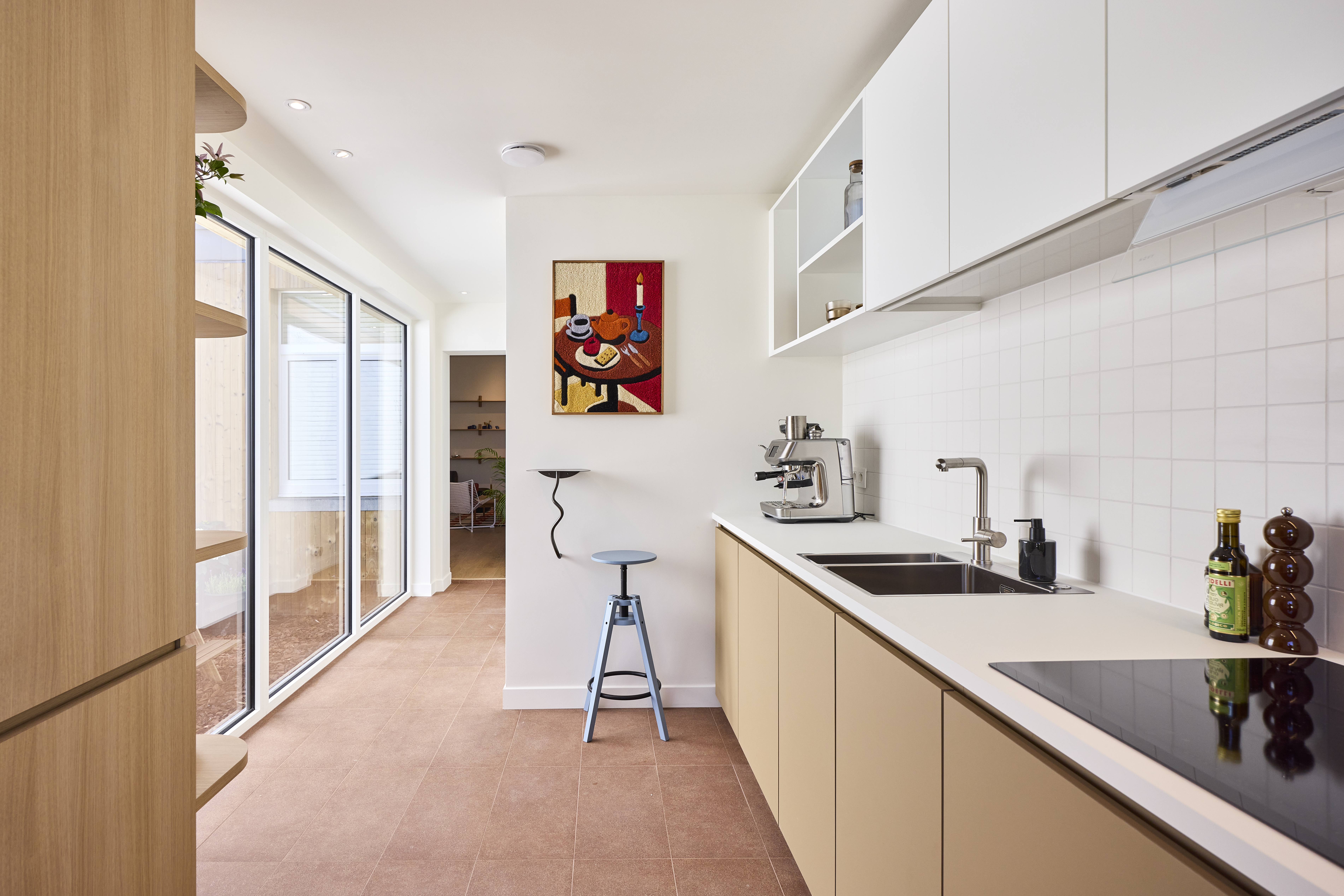 Lichte, moderne keuken met een Komfort EVO small-driedubbel raam en vast raam in verkeerswit, naast een houten kast en een lang keukenwerkblad.